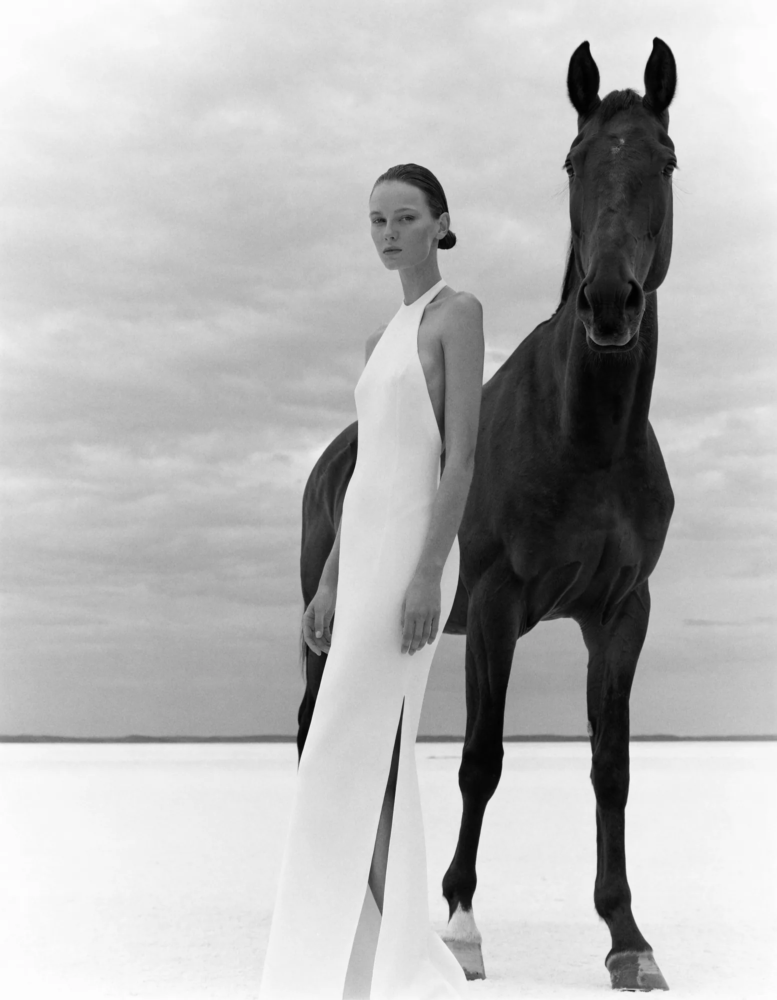 Editorial fashion portrait, woman in white gown beside a black horse on a salt flat — The Fine Cut