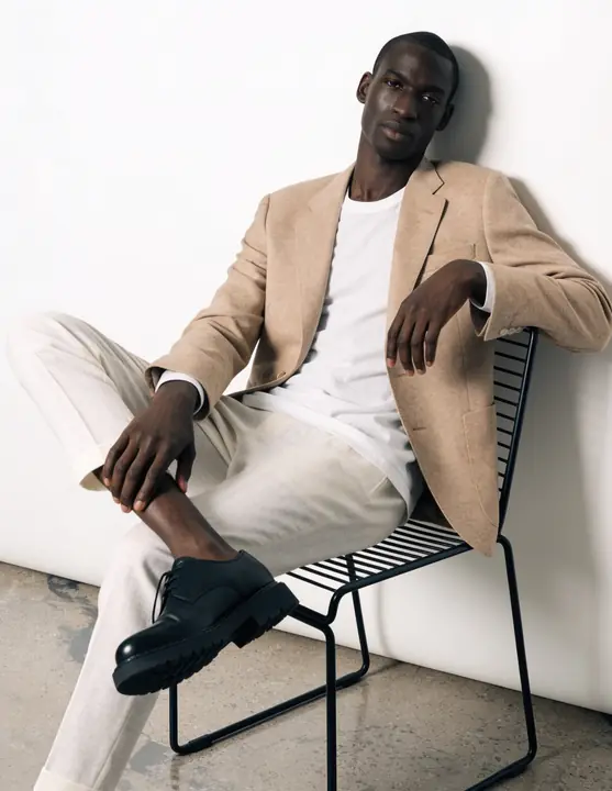 Camel blazer and white trousers in a minimal white studio