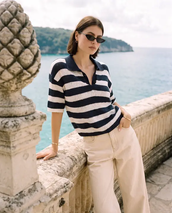 Striped knit polo and cream denim on a Mediterranean stone terrace