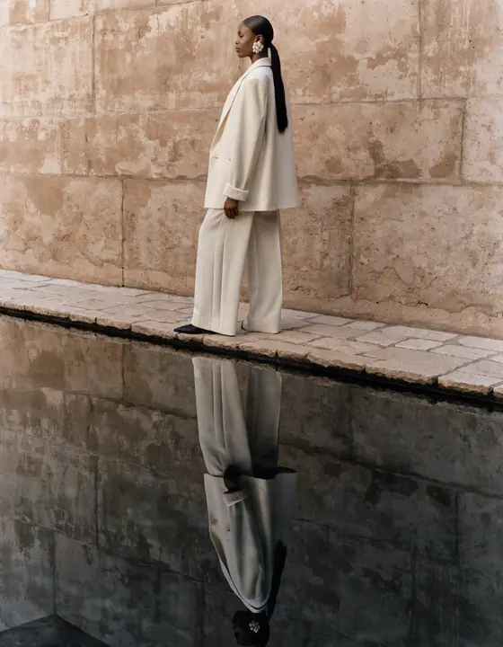 Cream tailored suit reflected in a travertine pool
